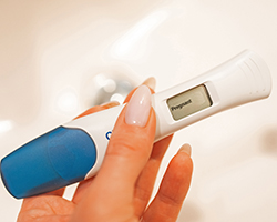 A hand holding a pregnancy test that reads &quot;pregnant.&quot;