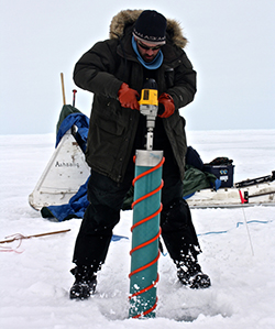 Researcher drills an ice core