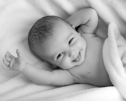 A happy baby wrapped in a blanket, shown in black and white