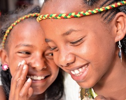 One Ethiopian girl whispering into the ear of another
