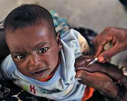 A young child receiving a vaccination through an arm injection.