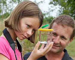 Young girl and older man show interest in an insect