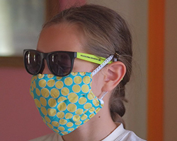 Girl wearing a colorful, protective mask, and sunglasses