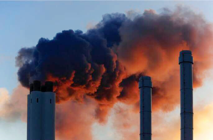 Smokestacks spewing dark black smoke into the sky.