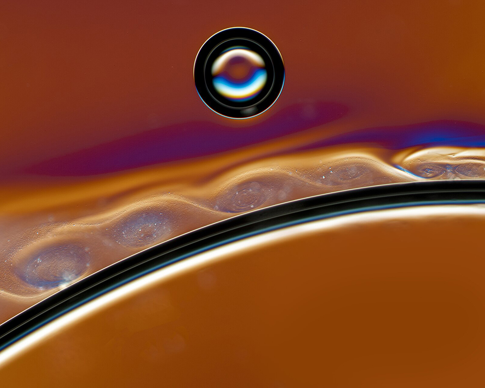 a close-up view of a fluid moving along a stationary object and causing ripples