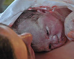 A newborn covered in a white filmy substance.
