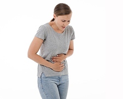 A young girl holding her stomach and partly bent over with stomach pain