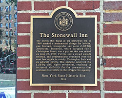 A brick wall with a plaque on it, which reads &quot;The Stonewall Inn&quot; and has a historical description underneath.