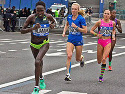 Three women are running a marathon, their names pinned to their chests on paper.