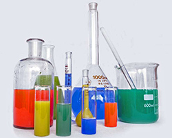 A collection of glass vials and beakers filled with colorful liquids.