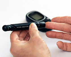 A blood sugar meter being used to prick the finger