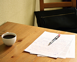 A cup of coffee on a table and a paper in the middle of being edited