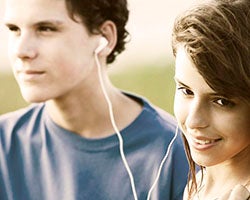 Teenagers sharing music through earbuds