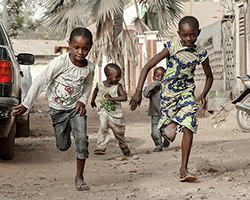 Four kids running down the street in Mali