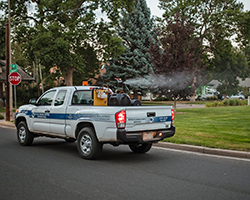 A pick up truck spraying insecticide into a park