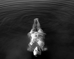 Black and white photo of woman floating in water