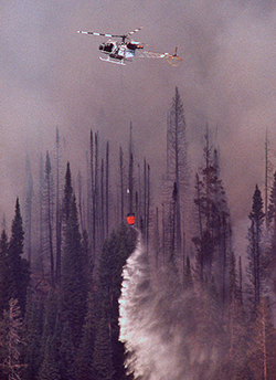 a helicopter, delivering a water drop to help fight a fire