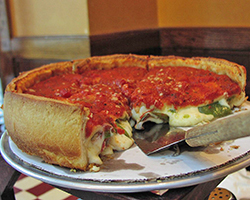 A deep dish chicago style pizza with a few slices cut away so you can see the stuffed filling.