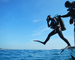 A scuba diver jumps off a boat into the water