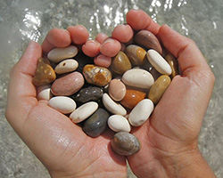 Two hands holding pebbles on the beach