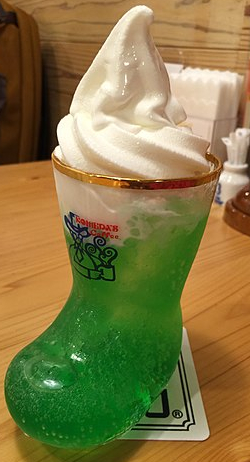 Green, cream soda topped with whipped cream served in a glass boot.