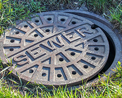 A sewer entry point with the manhole cover slid partly off
