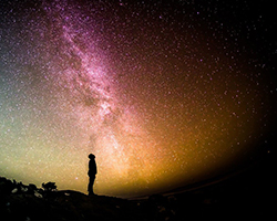 The silhouette of someone looking up at the milky way