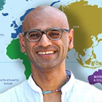 Arvind Varsani in front of a world map.
