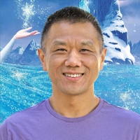 John Truong - artist, animator, and ant keeper. In front of a Frozen poster.