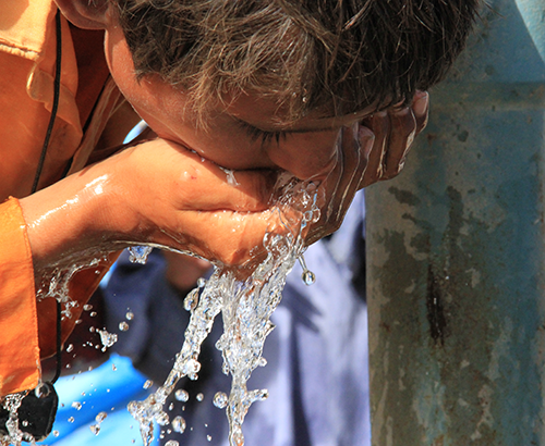 Boy drinking water from his hand