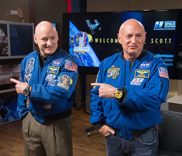 Twin astronauts Mark and Scott Kelly in matching blue NASA jackets.