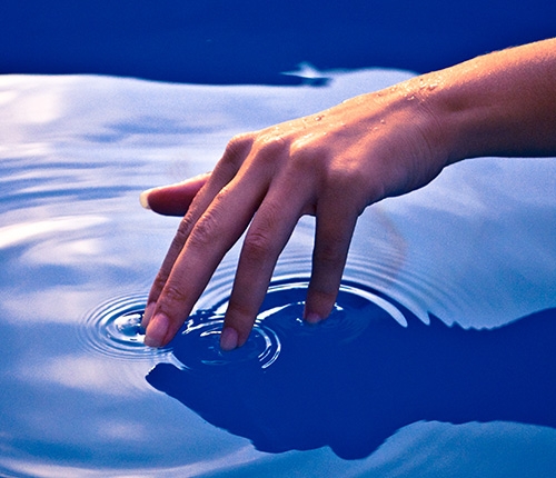 A hand touching a pool of water
